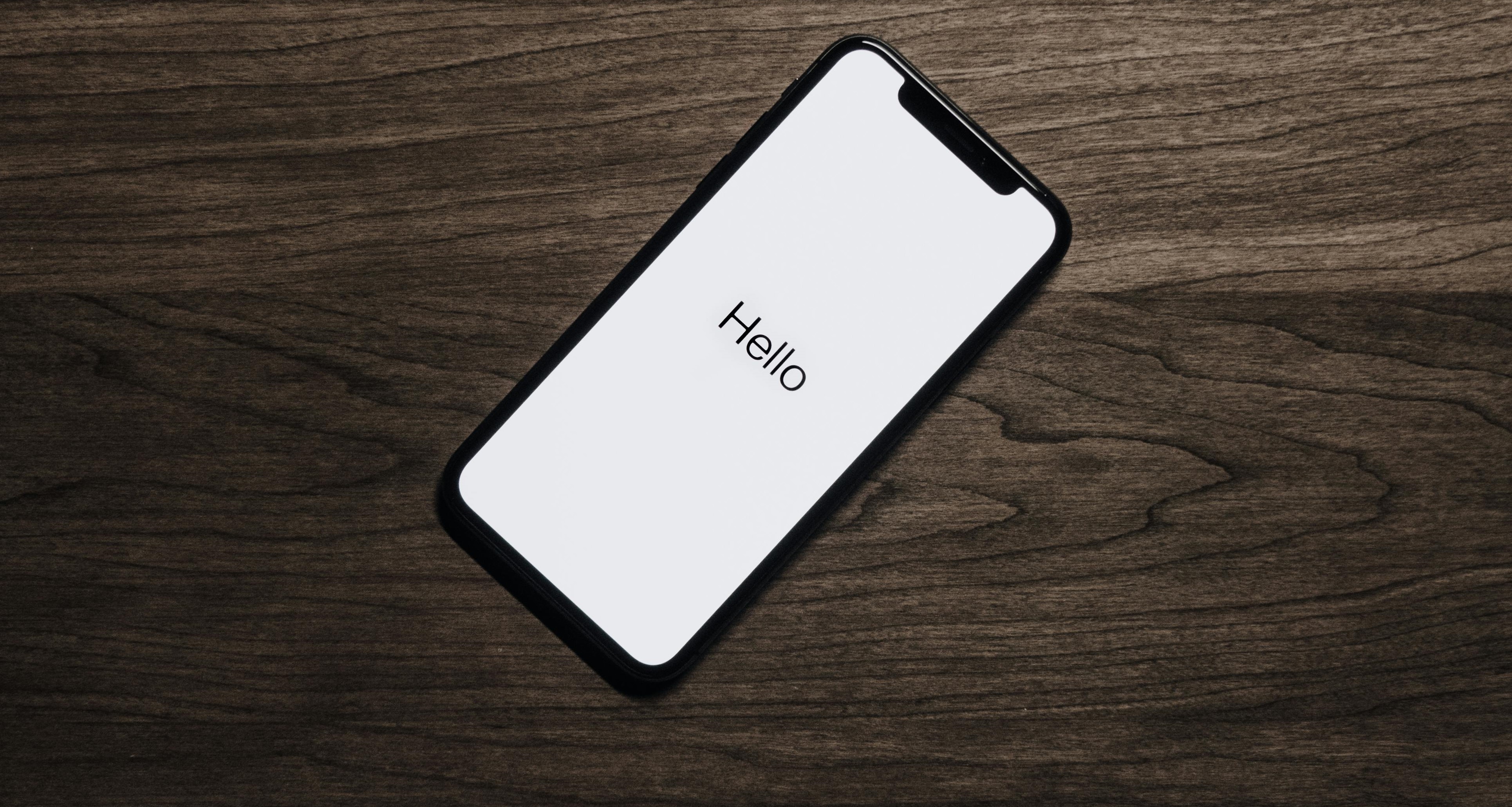 Cell phone on a desk with 'Hello' on the screen