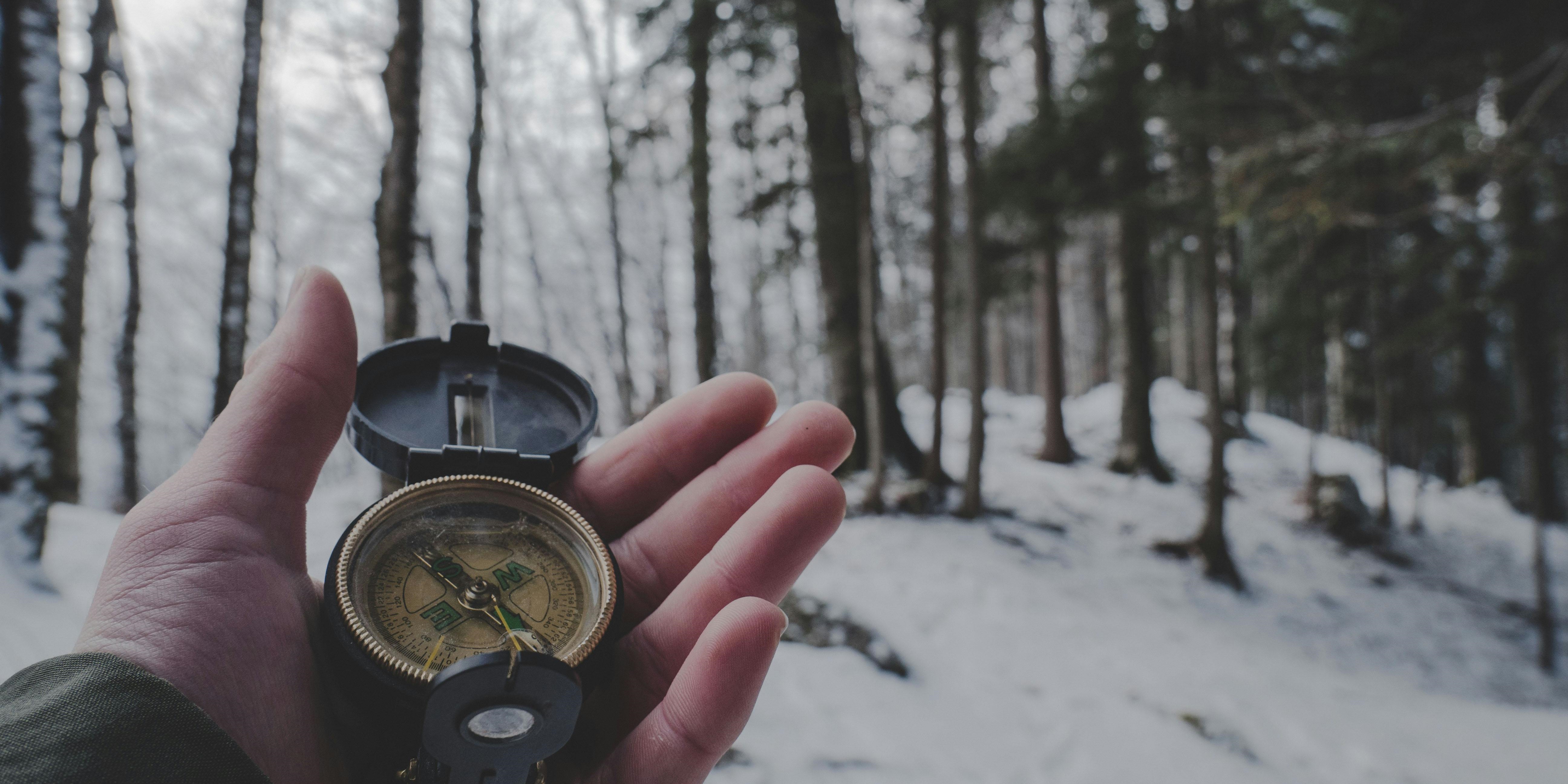 Hand holding a compass in snowy woods