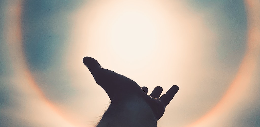 A hand reaching toward a bright light