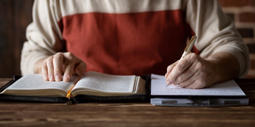 Person copying from a BIble into a notebook