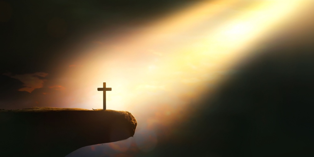 A sunbeam shining on a cross on the edge of a cliff