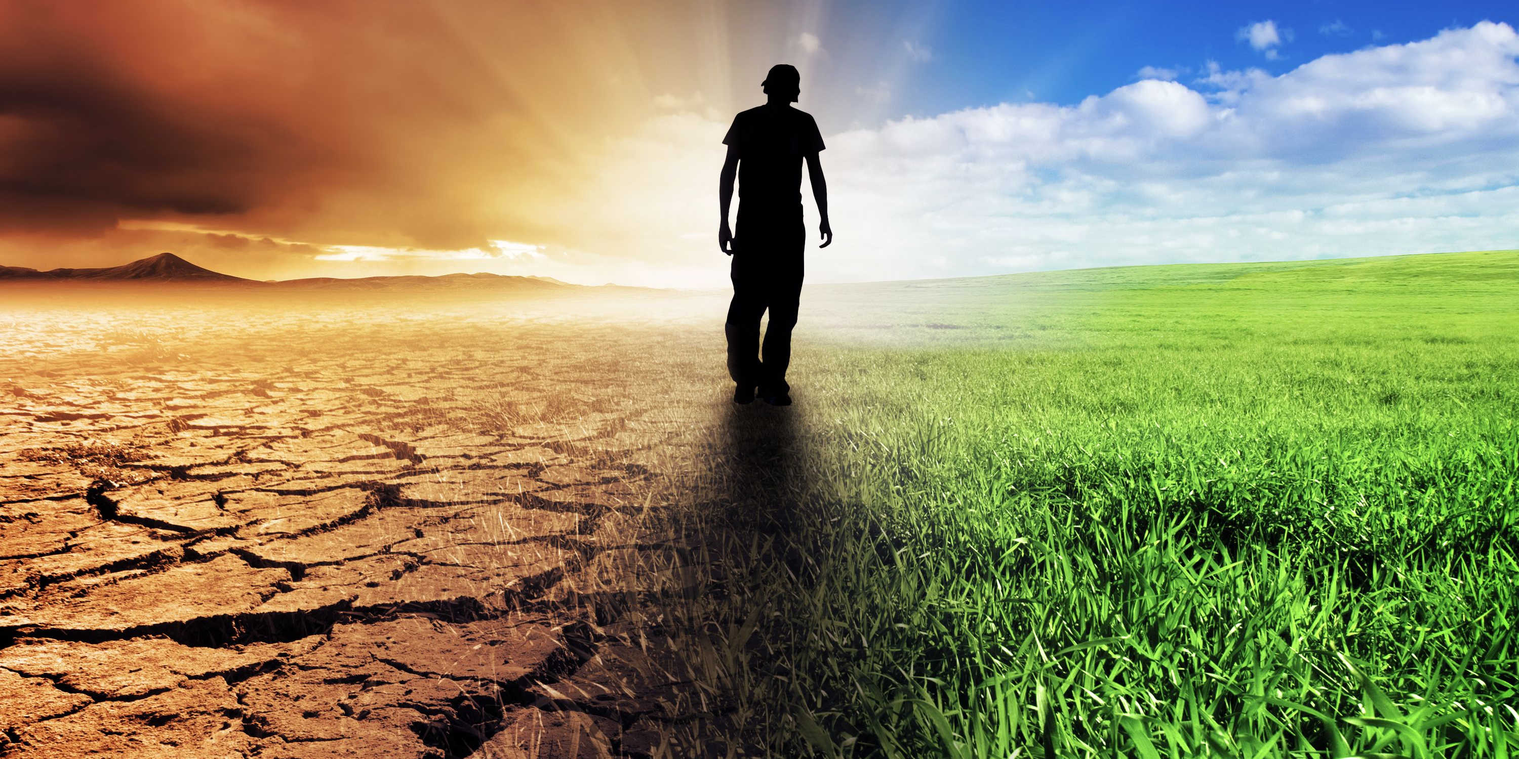 A man walking with desert on one side and green grass on the other