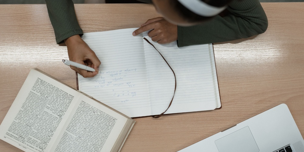 Writing in a notebook with open Bible