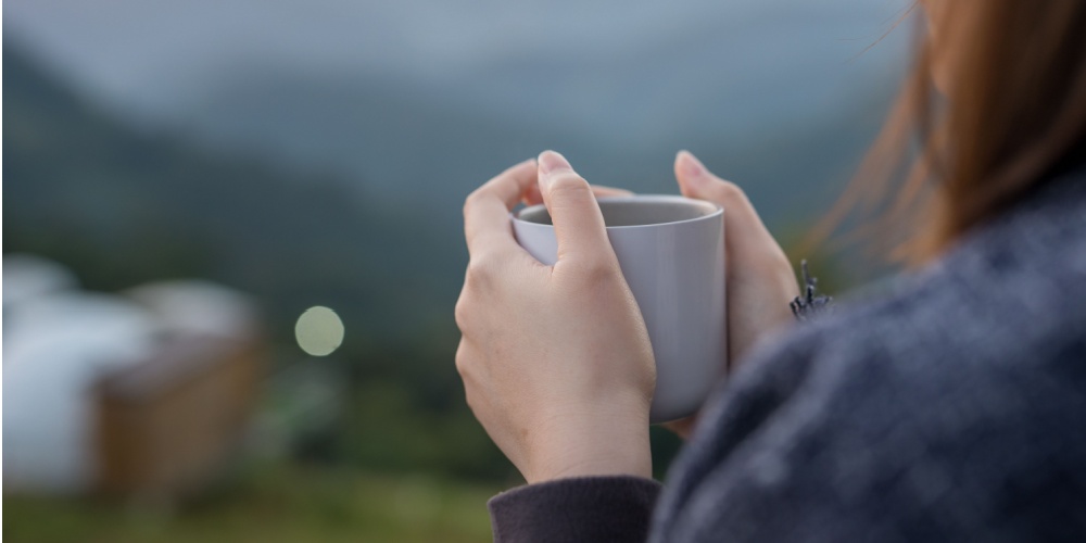 Woman holding a mug in front of a senic vista