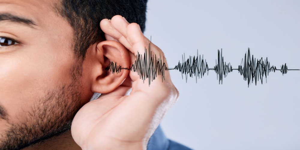 Illustrated sound wave entering a man's ear as he cups his ear with a hand