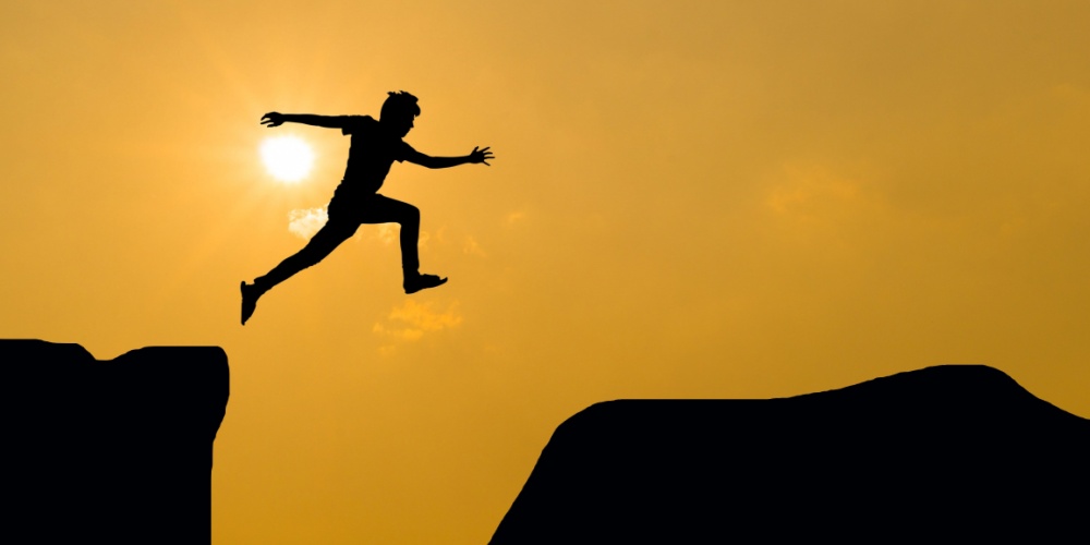 Jumping between large rocks in front of sunset