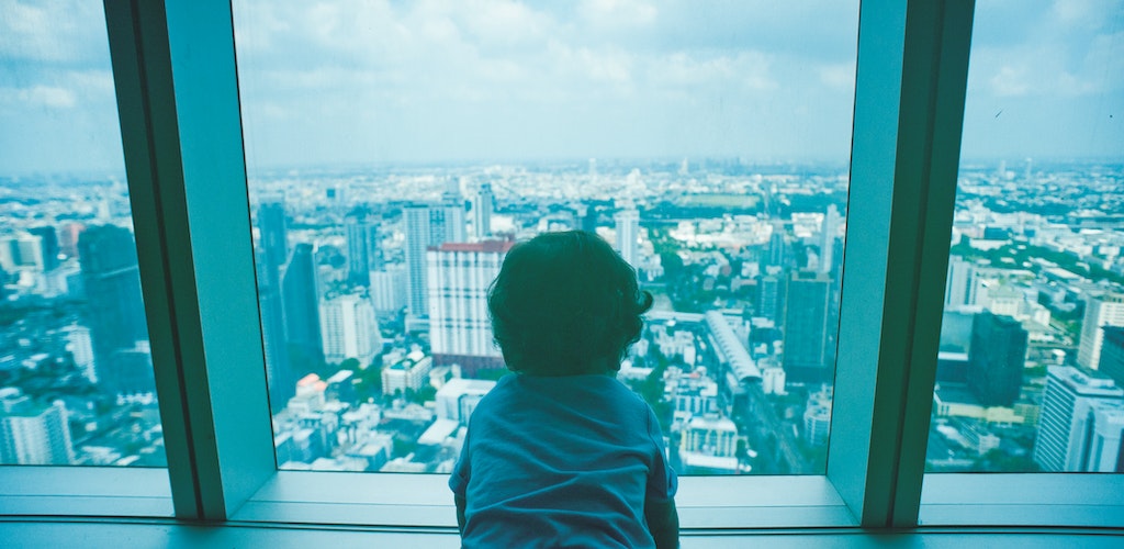Child looking out the window of a skyscraper